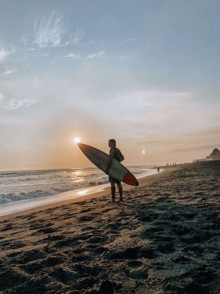 Male surfer in the black-sand beach of El Paredon.