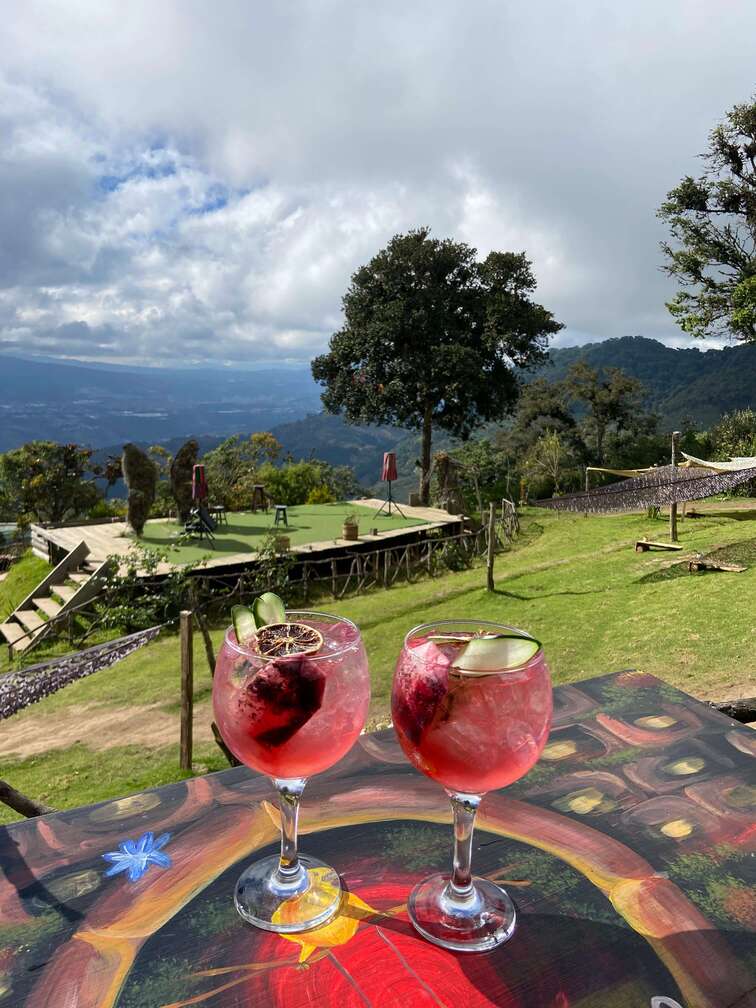 Pink cocktails in Hobbitenango with the mountains in the background.